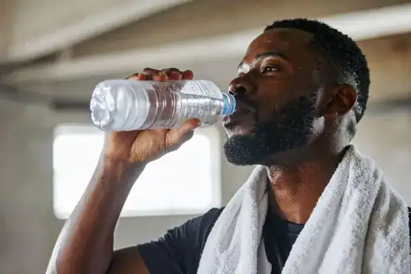 Hydration: The Secret Ingredient for a Toned Stomach and Enhanced Fitness 1 Image of man drinking water to improve hydration Horley after work out.